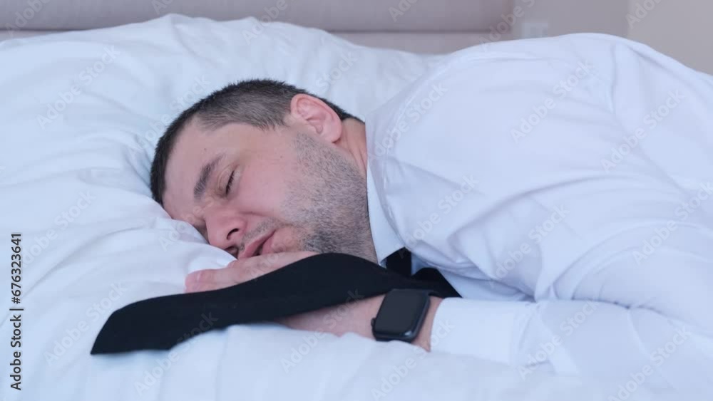 A man in formal wear resting on a bed during a business trip. Overworked at work A man in formal wear resting on a bed during a business trip. Overworked at work