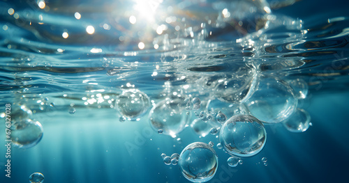 Air bubbles ascend in clear blue water, catching the light on their way to the surface.