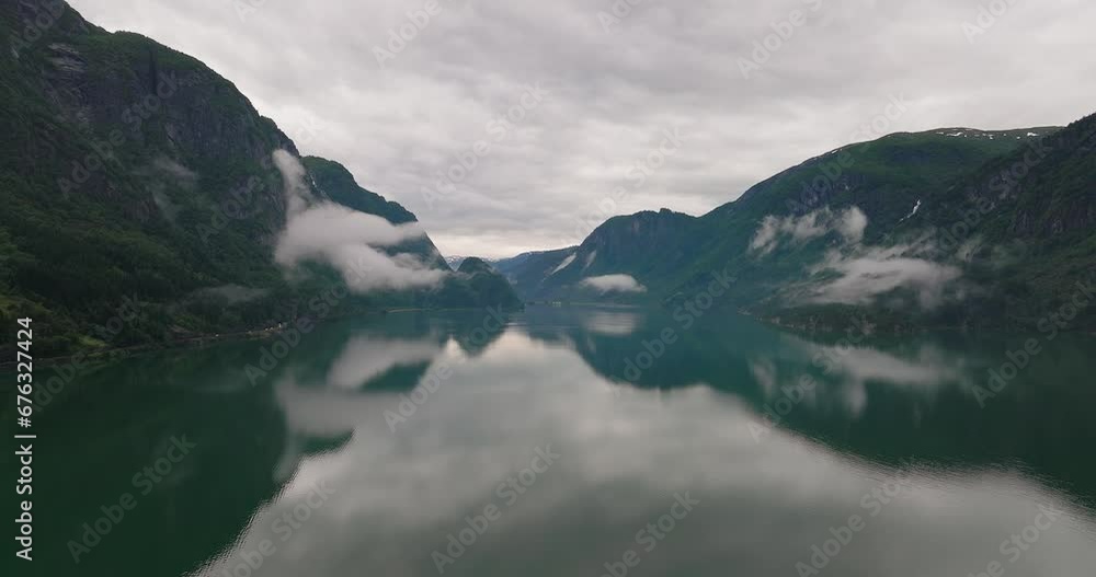 Stunning view of still lake water reflecting mountainous range and sky Stunning view of still lake water reflecting mountainous range and sky
