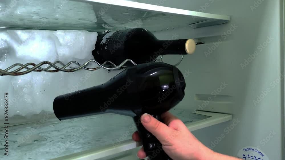Descongelando el hielo de una nevera con la ayuda de un secador de pelo.