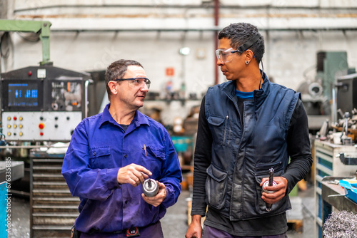 Instructor teaching and speaking the trade to a metal industrial factory worker in the numerical control sector © unai