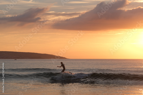 Fototapeta Naklejka Na Ścianę i Meble -  Surfer at Sunset off the Cornish Coast 