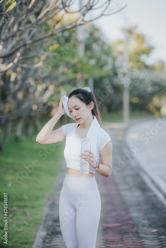 Happy Asian woman wearing sportswear jogging in the park Beautiful young Asian woman in sports bra running outdoors The concept of a healthy and active lifestyle