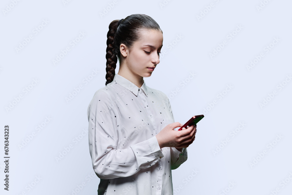 Teenage student girl using smartphone on white studio background Teenage student girl using smartphone on white studio background