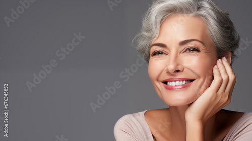 Beautiful aging young looking and smiling woman. Advertising concept for cosmetics and beauty products. Gray hair and healthy skin.