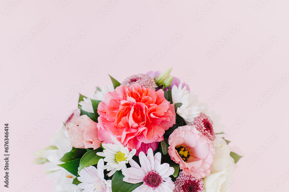 Beautiful bouquet of pink. violet and white flowers on a pink pastel background.