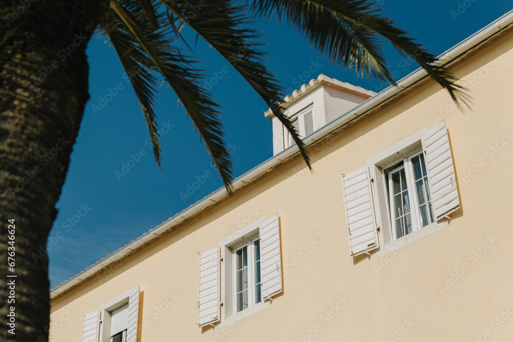 Building with white shutters and palm tree in Supetar, Croatia. Blue sky on a background.