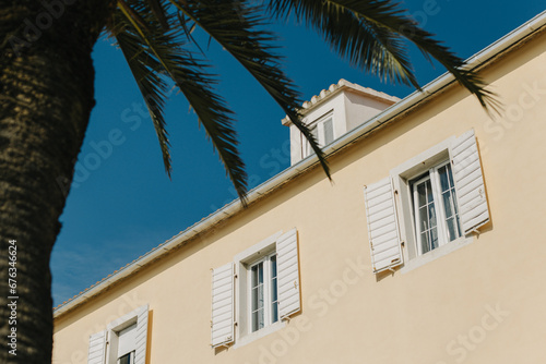 Building with white shutters and palm tree in Supetar  Croatia. Blue sky on a background.