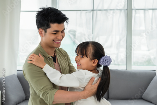 dad dances with his daughter. young happy dad dancing with his daughter, little girl with ponytails in a dress dancing with her dad