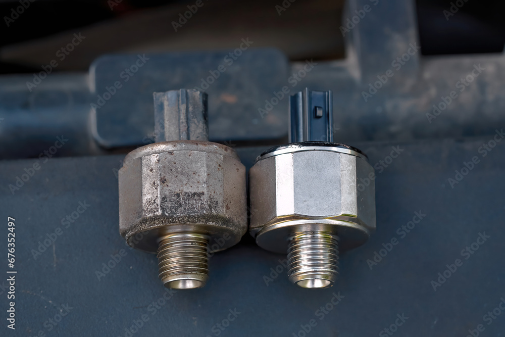 Knock sensor. Replacing broken engine knock sensor, engine detonation. Bad knock sensor and new one ready to replace. Faulty knock sensor, engine problems. Car maintenance. Selective focus Knock sensor. Replacing broken engine knock sensor, engine detonation. Bad knock sensor and new one ready to replace. Faulty knock sensor, engine problems. Car maintenance. Selective focus