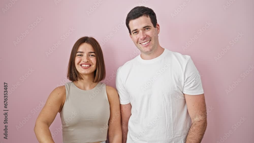 Beautiful couple standing together bumping fists smiling over isolated pink background Beautiful couple standing together bumping fists smiling over isolated pink background
