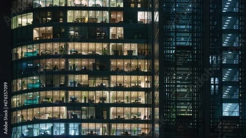 Time lapse office windows lights in business center building facade, people working late night. Corporate business, high skyscraper glass surface. Light in building windows turn on and off in evening photo