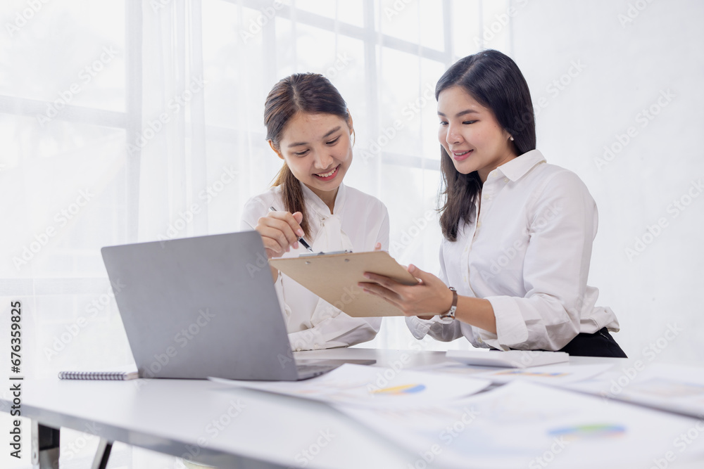 Two asian confident business women point to graphs and charts to analyze market data, balance sheet, account, net profit to plan new sales strategies to increase production capacity. Two asian confident business women point to graphs and charts to analyze market data, balance sheet, account, net profit to plan new sales strategies to increase production capacity.