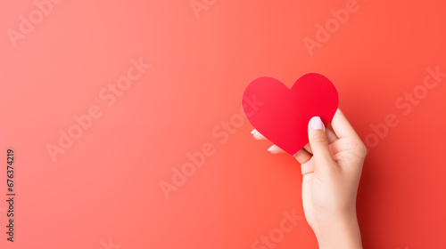 Hand holding blank paper greeting or invitation card over red background with heart shape. Christmas, Valentine day, New Year, winter holidays concept.