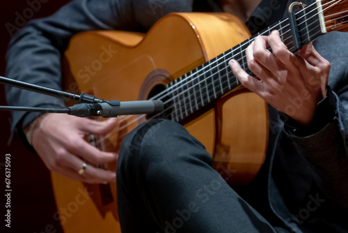 The singer plays an acoustic guitar. Close up of man's hands playing acoustic guitar