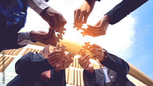 The hand of a businessman holding a paper jigsaw And solve the puzzle together. The business team assembled a jigsaw puzzle. A business group wishing to bring together the puzzle pieces photo