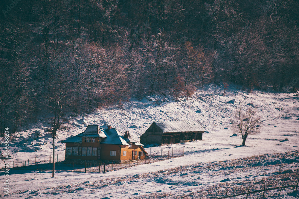 Ancient romanian houses on the frozen hills in the middle of winter. Wonderful landscape in the cold season with rustic buildings at the foot of the high mountains