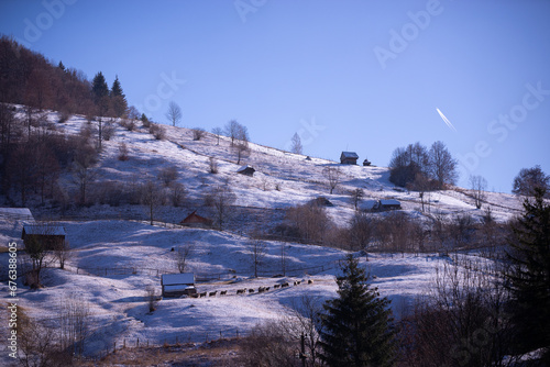 Ancient romanian old barn on a frosty day. Wooden construction at the base of the high mountains in the winter season