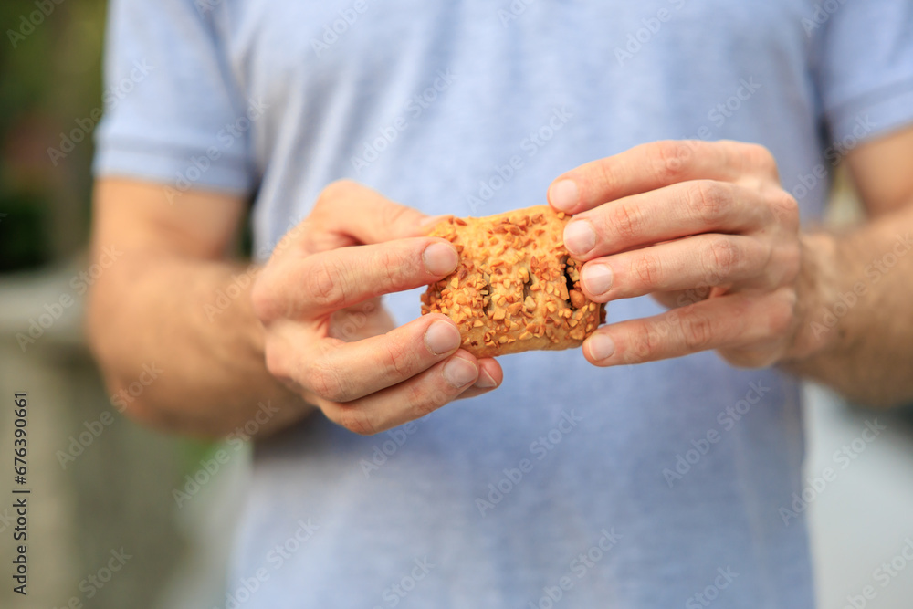 A man's hand holds sweet pastry with jam, snack and fast food concept. Selective focus on hands with blurred background A man's hand holds sweet pastry with jam, snack and fast food concept. Selective focus on hands with blurred background