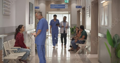 Tracking Dolly Shot of Hospital Corridor and Lobby Filled with Group of Diverse Indian Patients Waiting for their Appointments. Modern Health Clinic with Active Doctors, Nurses and Staff Working