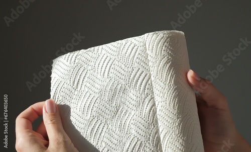 Female hands tear off piece of white paper towel from a roll