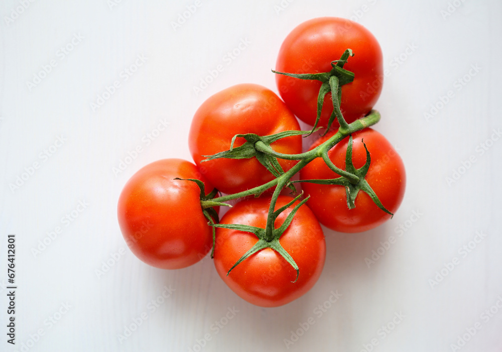 ripe tomatoes on branch on white surface