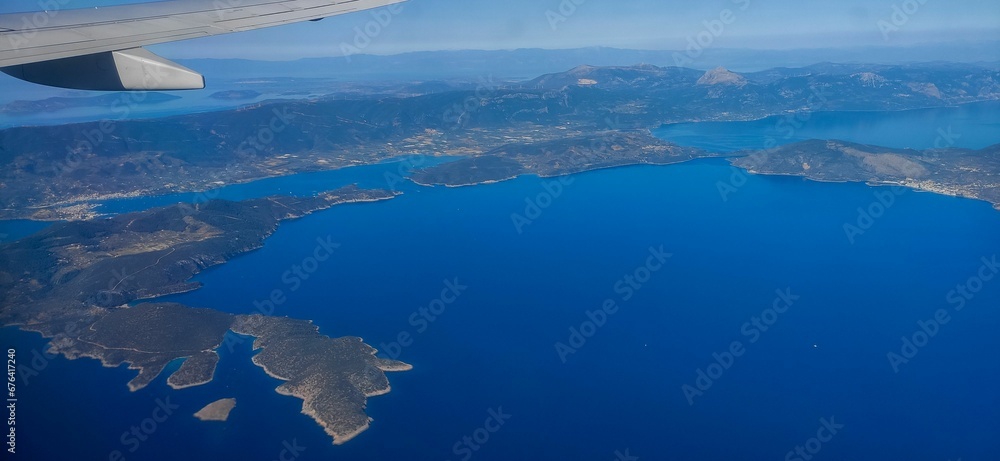Gorgeous aerial view of a deep blue sea surrounded by islands from an airplane with the wing visible