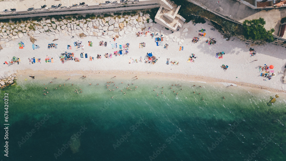 Top view, splendid aerial view of some people relaxing on a beautiful beach washed by the sea. Bisceglie (Apulia, Italy)
