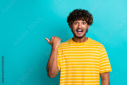 Photo portrait of nice young male point impressed empty space dressed stylish striped yellow garment isolated on cyan color background
