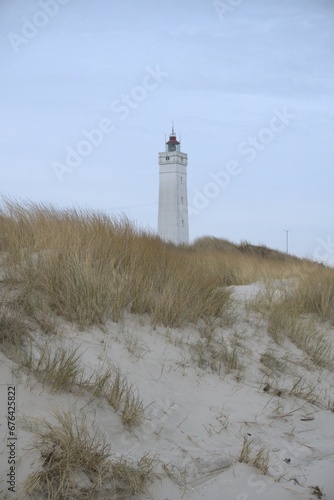 Vertical shot of the lighthouse on a sandy beach on a background of a blue sky
