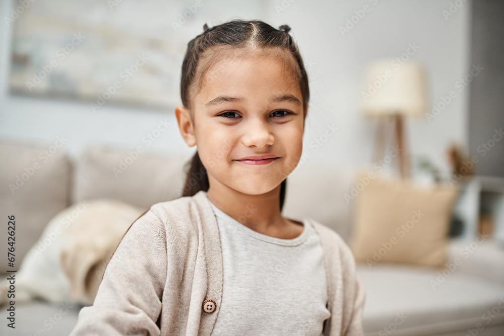 portrait of happy elementary age girl with brunette hair smiling at camera in modern apartment portrait of happy elementary age girl with brunette hair smiling at camera in modern apartment