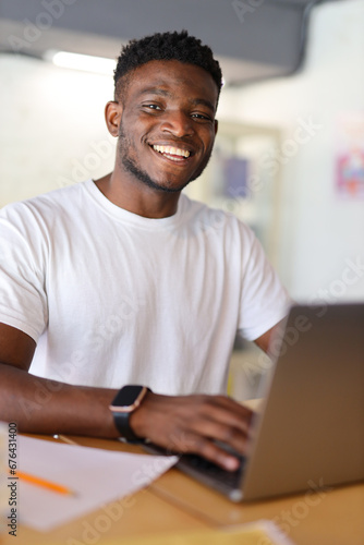 Confident African American businessman working on a laptop from home, embodying a modern and successful professional lifestyle.