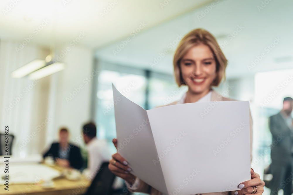 Fototapeta premium Shot of a smiling young businesswoman standing in a modern office with some papers