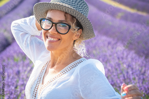 Portrait of happy young woman smiling and enjoying leisure outdoor activity with lavender field flowers in background. Travel and summer holiday vacation tourit female people. Attractive joy lady photo
