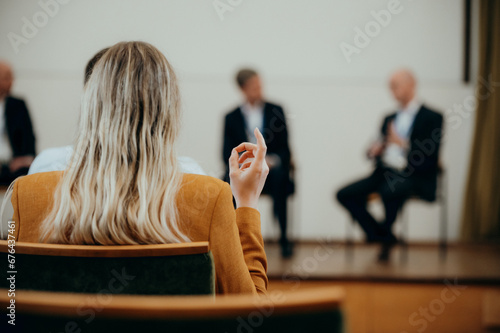 Image Foto - Frau erhebt ihre Hand bei einer Podiumsdiskussion auf einem Kongress