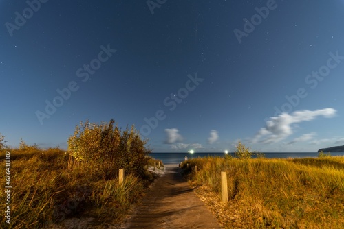 Long exposure shot of a starry night sky over a beach path in the Baltic Sea.