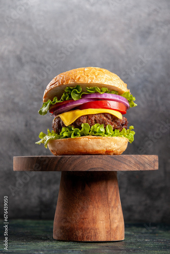 delicious homemade burger of beef, cheese and vegetables on an table. Fat unhealthy food close-up, burger with cheese, bacon, salad and vegetables on wooden board, hamburger with lettuce, cheeseburger