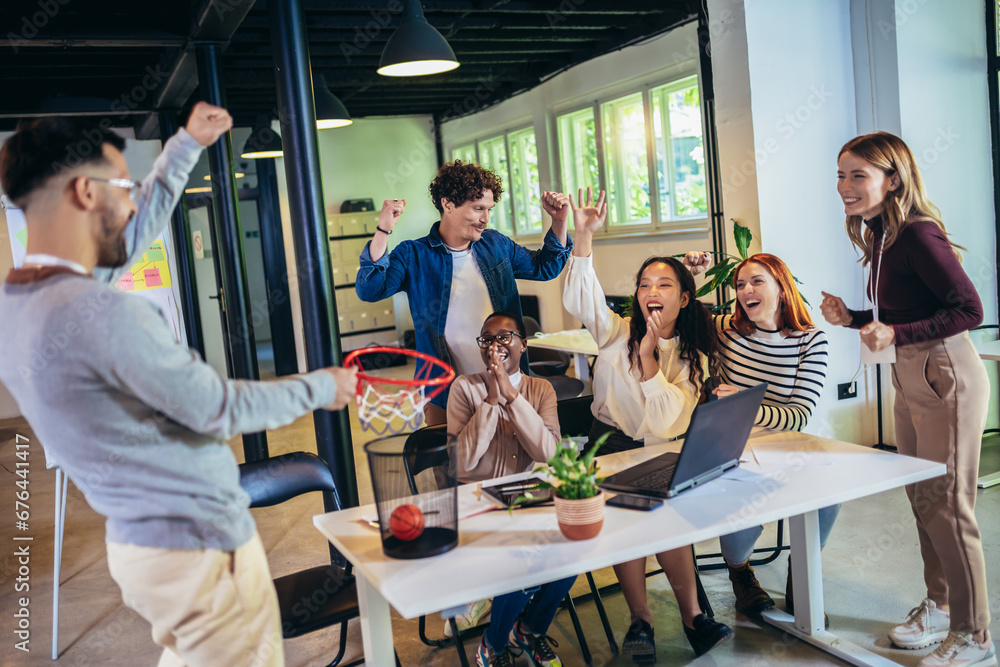 Obraz premium Young business people working together in the modern office have fun with basketball. Teamwork startup concept