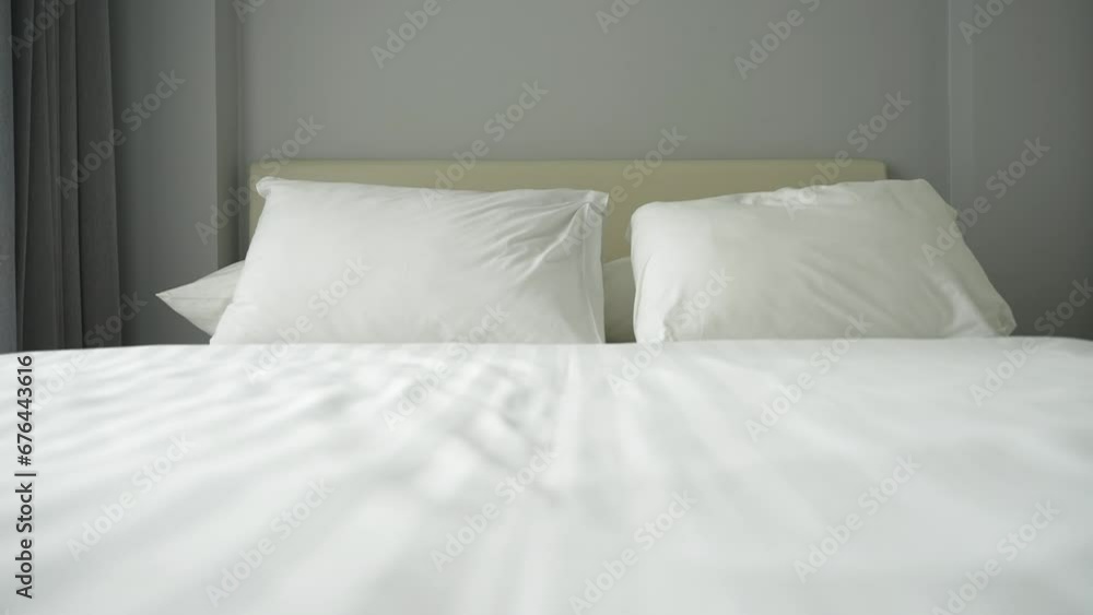 Close up of empty twisted bed with white bedding sheet near the window at day in the bedroom of the apartment. Calm sleep and relaxation at home Close up of empty twisted bed with white bedding sheet near the window at day in the bedroom of the apartment. Calm sleep and relaxation at home