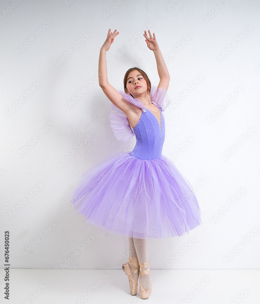 Young ballerina in a purple dress on a white background.