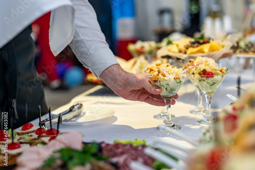 Fototapeta Naklejka Na Ścianę i Meble -  hands of a waiter prepare food for a buffet table in a restaurant