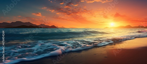The beautiful sunset paints the sky with shades of orange and blue creating a breathtaking backdrop for the beach as gentle waves kiss the shore and the warm summer sun bathes the landscape © TheWaterMeloonProjec