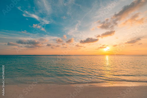 Beautiful sunset horizon sea or ocean. Vibrant soft colors magic sunlight. Small clouds yellow golden sky, reflection of sun water sand on beach. Peaceful romantic vacation in tropical island paradise © icemanphotos