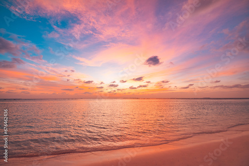 Beautiful sunset horizon sea or ocean. Vibrant soft colors magic sunlight. Small clouds yellow golden sky, reflection of sun water sand on beach. Peaceful romantic vacation in tropical island paradise © icemanphotos