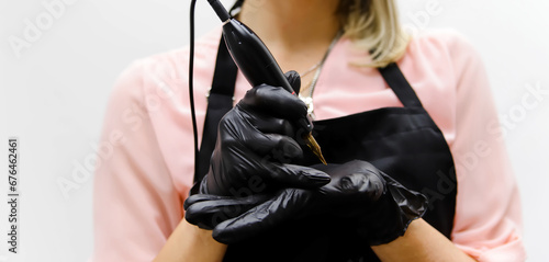 tattoo instrument for Permanent Makeup in hands wearing black medical gloves
