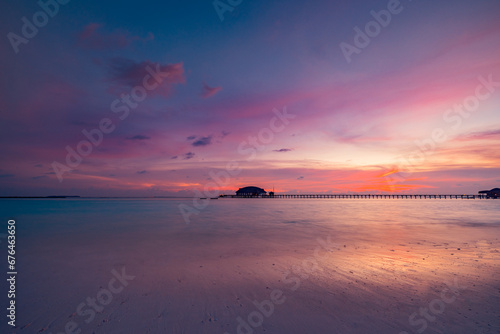 Amazing sunset panorama at Maldives. Luxury resort villas seascape with soft led lights under colorful sky. Beautiful twilight sky and colorful clouds. Beautiful beach background for vacation holiday 