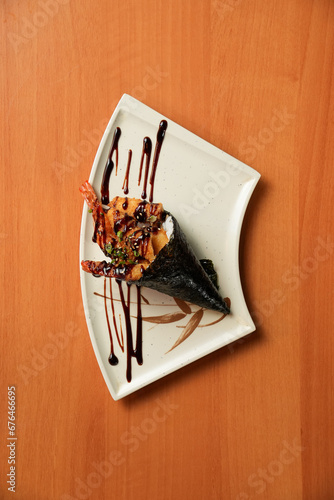 Foto temaki de camarão empanado com arroz, enrolado em uma nori, coberto por cebolinh