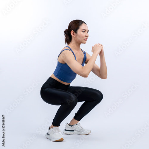 Vigorous energetic woman doing exercise. Young athletic asian woman strength and endurance training session as squat workout routine session. Full body studio shot on isolated background.