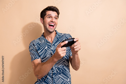 Photo of crazy young guy playing video games holding joystick addicted gamer enjoying weekend vacation isolated on beige color background #676471477