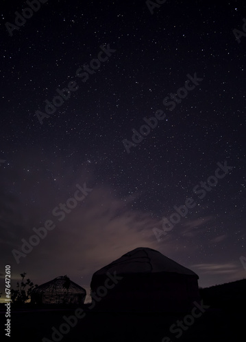 Yurts in the darkness of the night against the backdrop of the starry sky in the desert